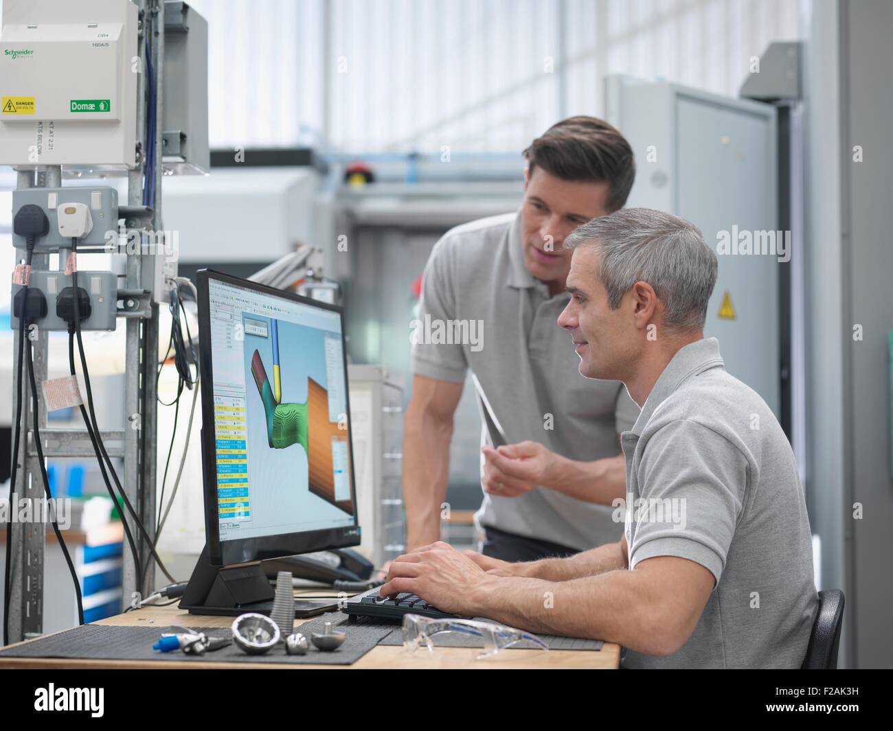 Ingenieros viendo progresos en torno CNC pantalla en fábrica de ortopedia Foto de stock