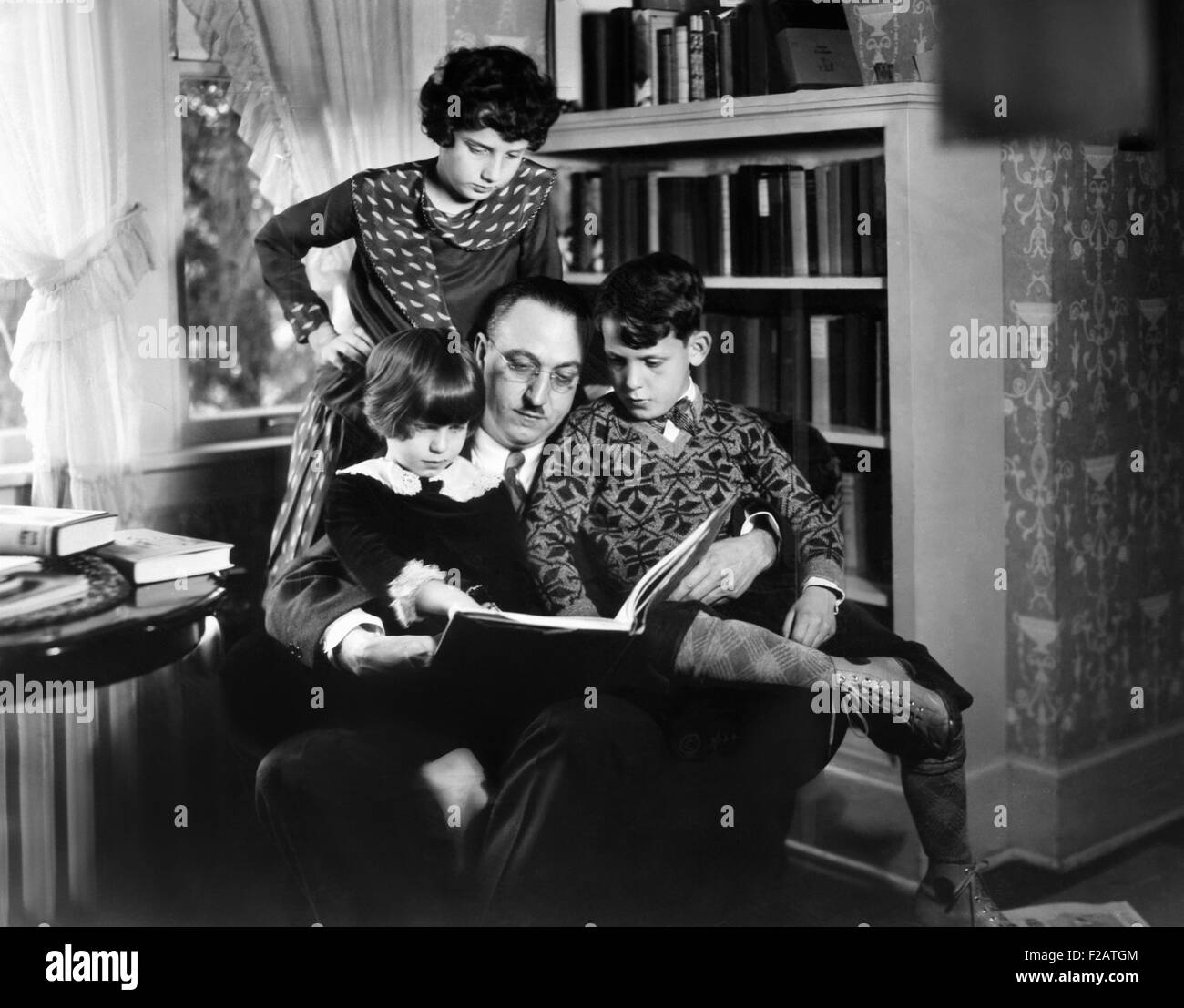 El Dr. Karl A. Menninger, psiquiatra, con sus hijos. Ca. 1930. Están jugando el anagrama. Julia está de pie, mientras Marta y Robert sentarse con su padre. (CSU 2015 11 1627) Foto de stock