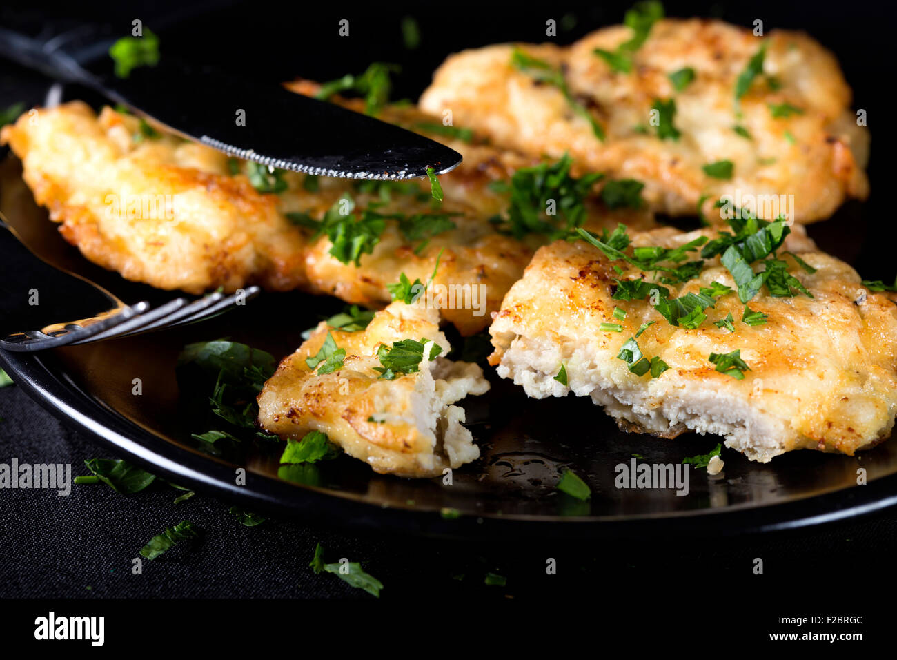 Fried Chicken schnitzel con perejil sobre placa oscuro Foto de stock