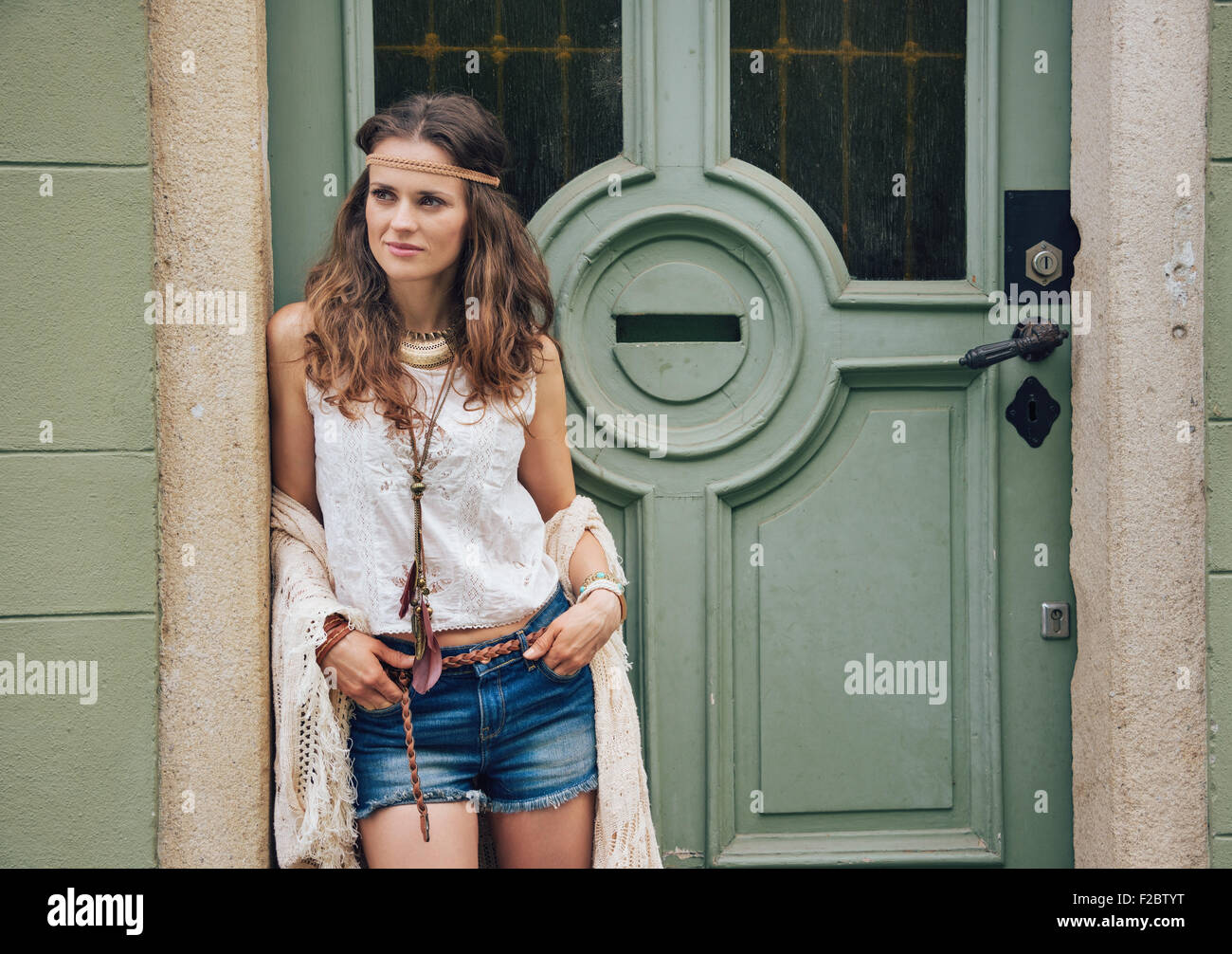 Outdoor retrato de moda moda joven hipster en pantalones cortos, blusa  blanca y mantón tejido exterior permanente contra Fotografía de stock -  Alamy