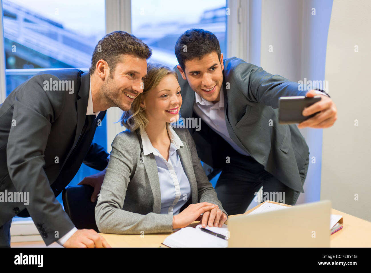 Retrato de tres empresarios sonriente tomando un selfie con el smartphone Foto de stock