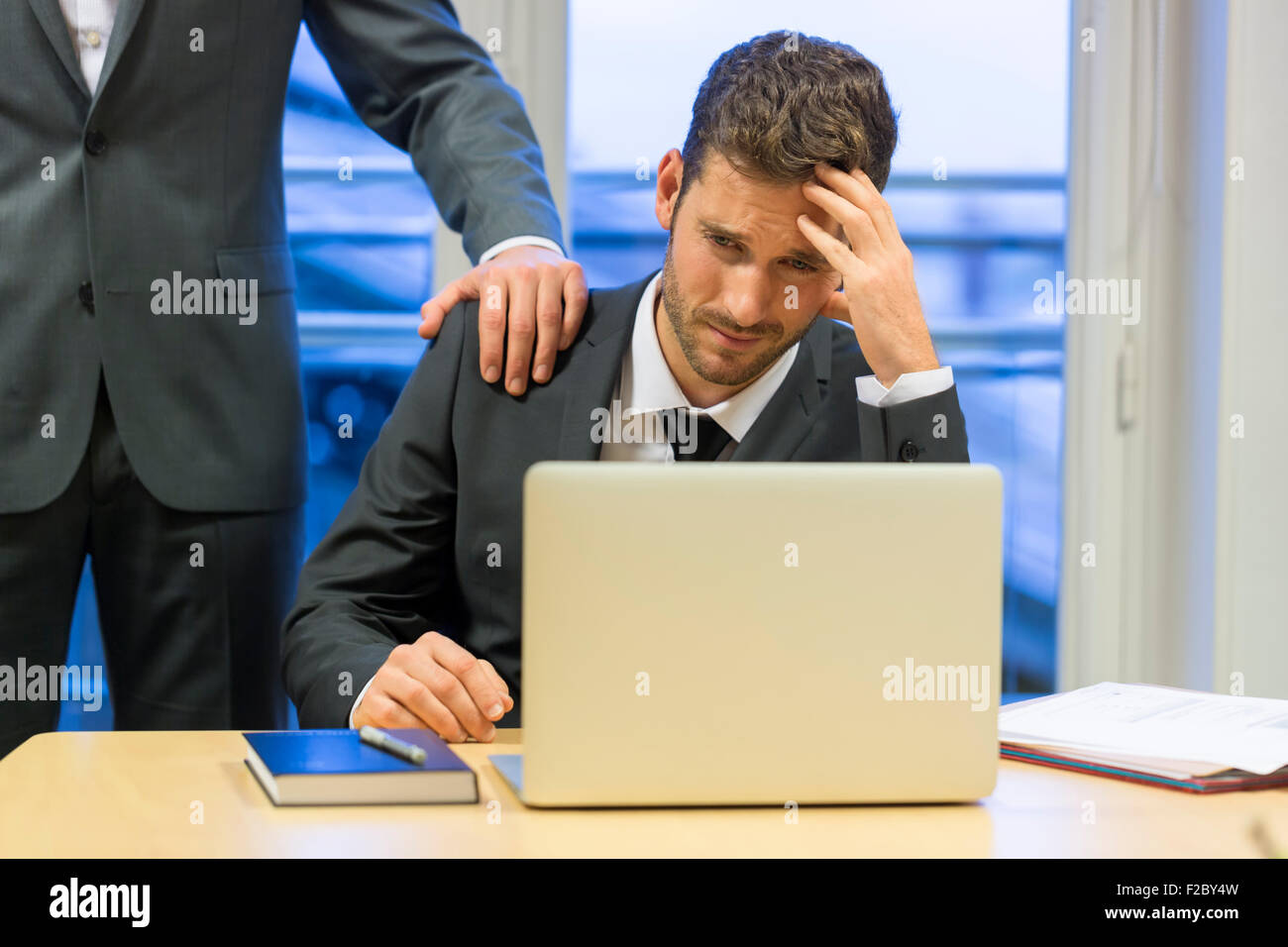 Hombre de negocios frustrado utilización portátil con su colega en su oficina Foto de stock