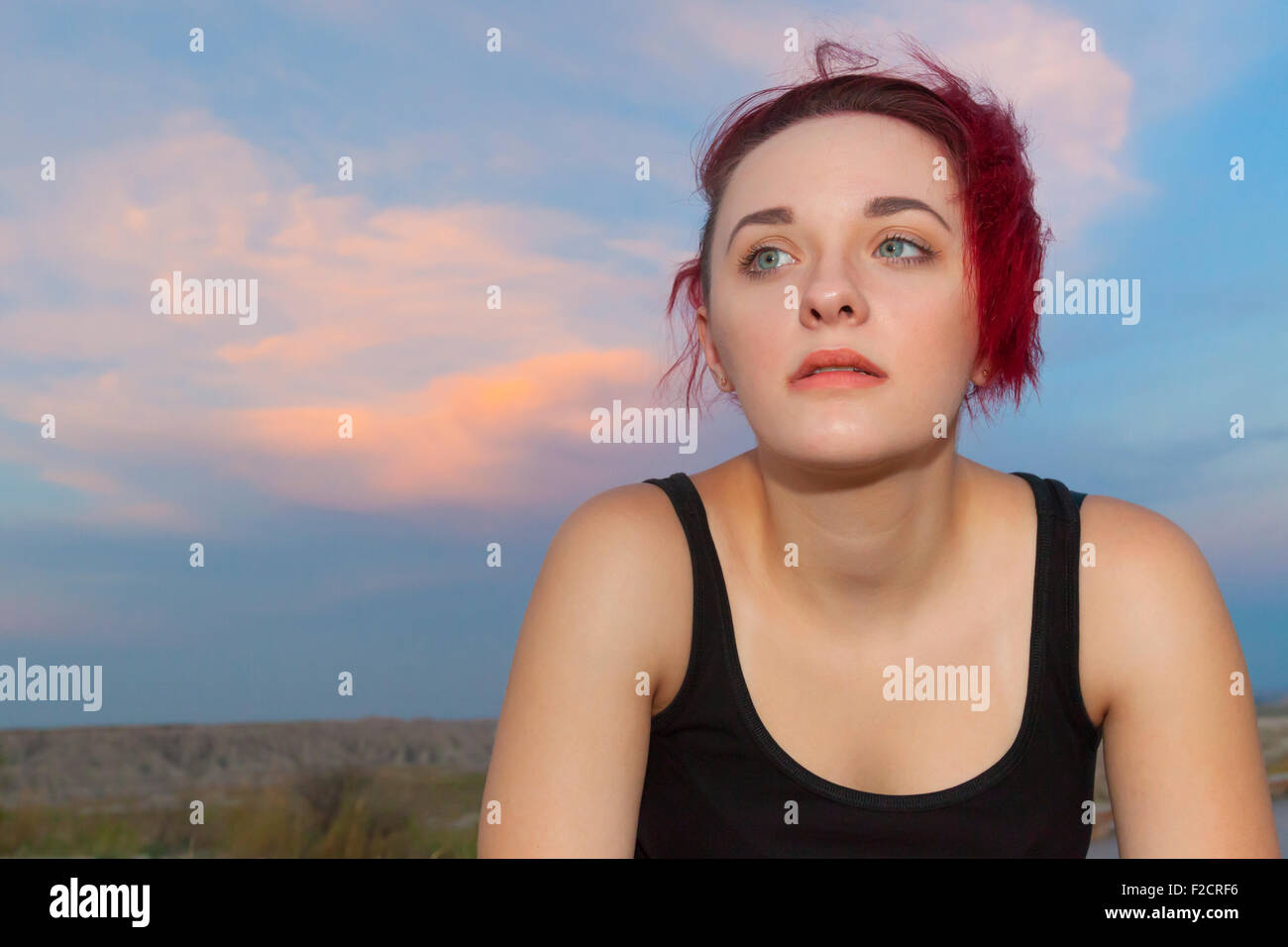 Una atractiva mujer joven posando con pensativo, serio y tonto expresiones afuera contra un cielo azul. Foto de stock