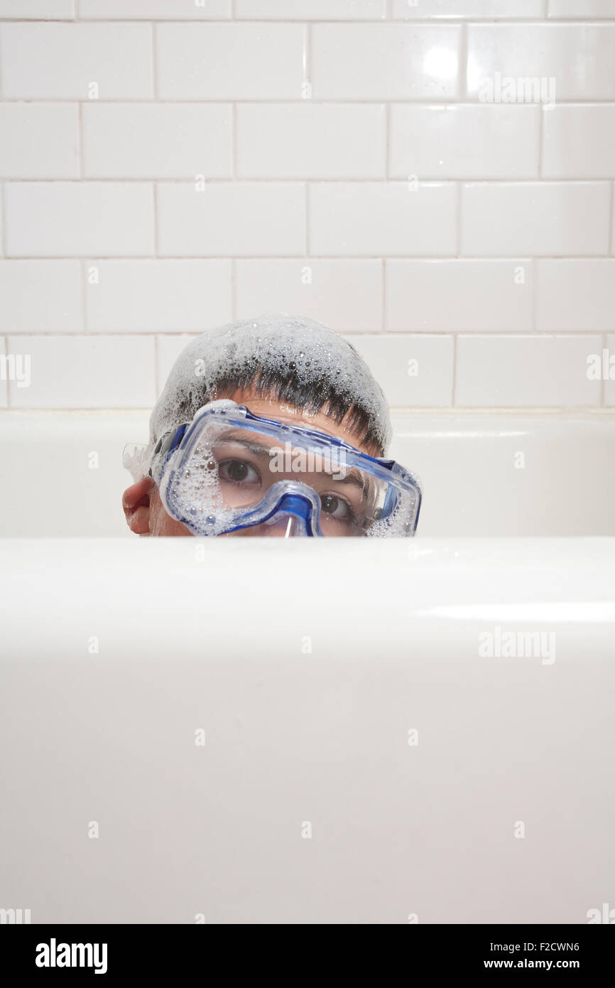 Sudsy, húmedo, joven con gafas pares sobre la bañera en el baño blanco Foto de stock