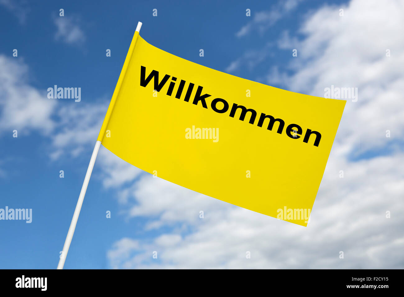 Bandera amarilla bienvenido delante de un cielo azul Foto de stock