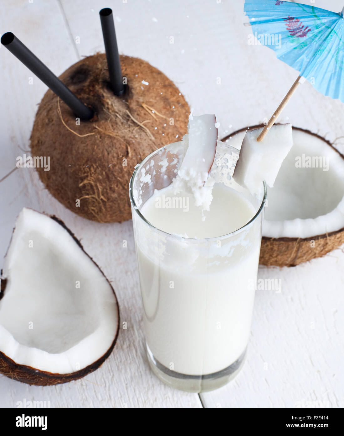 Spalsh bebida con leche de coco y mesa de madera blanca. Foto de stock