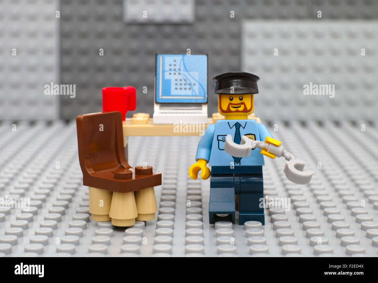 Policía minifigure Lego con esposas va a arresto desde su lugar de trabajo  con el equipo y la taza en la placa base gris de Lego Fotografía de stock -  Alamy