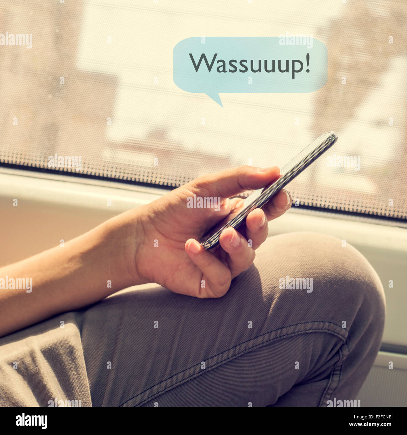 Primer plano de un joven en un vagón de tren enviar un mensaje de texto con su smartphone con el texto wassuuuup Foto de stock