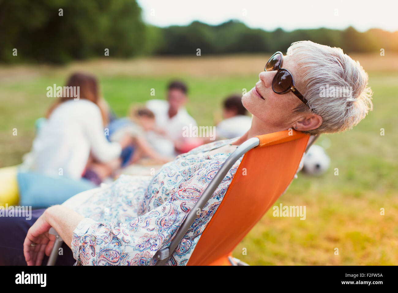 Mujer senior en la silla relajante en el campo Foto de stock
