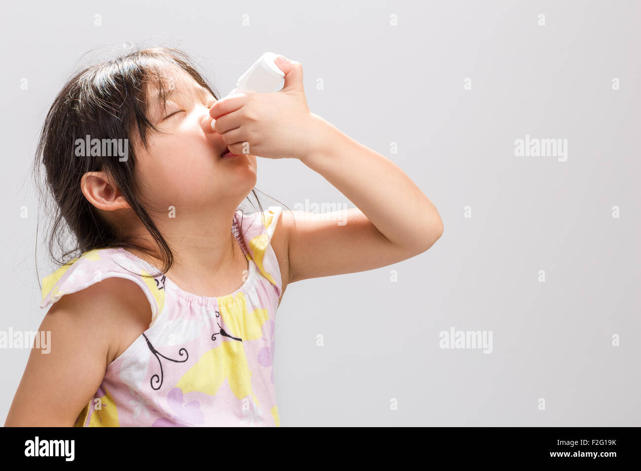 Enfermos chica asiática medicina nasal spray en la nariz. Foto de stock
