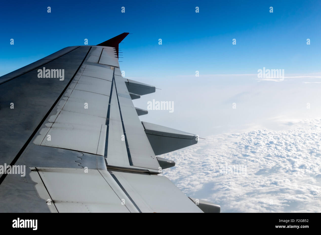 Cielo nublado y ala de avión como se ve a través de la ventana de una aeronave. Foto de stock