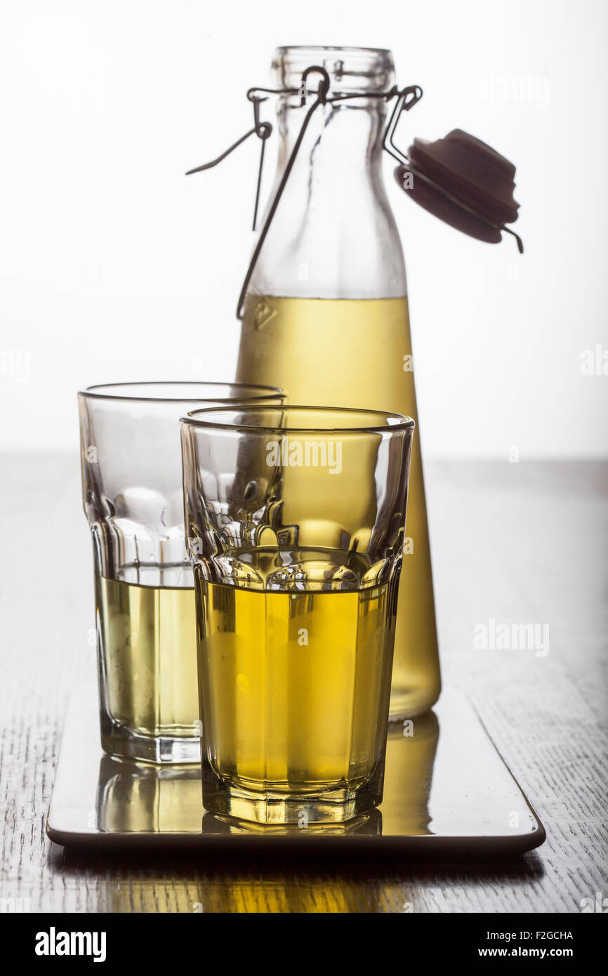 Foto retroiluminada de limoncello casero en botella con dos vasos en la bandeja Foto de stock