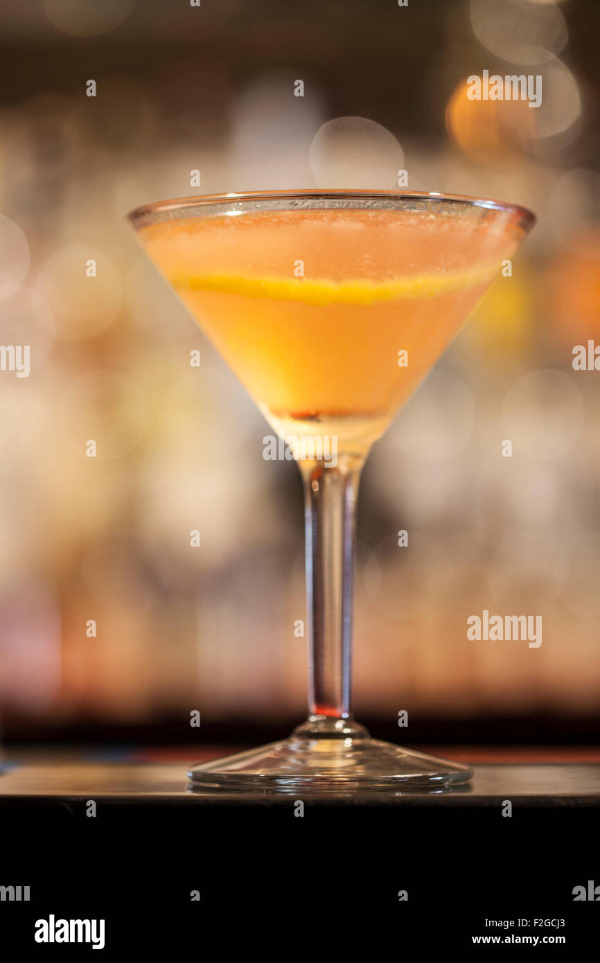 En el bar de cócteles, iluminada desde atrás, en martinit cristal con toque de limón y fuera de foco antecedentes Foto de stock