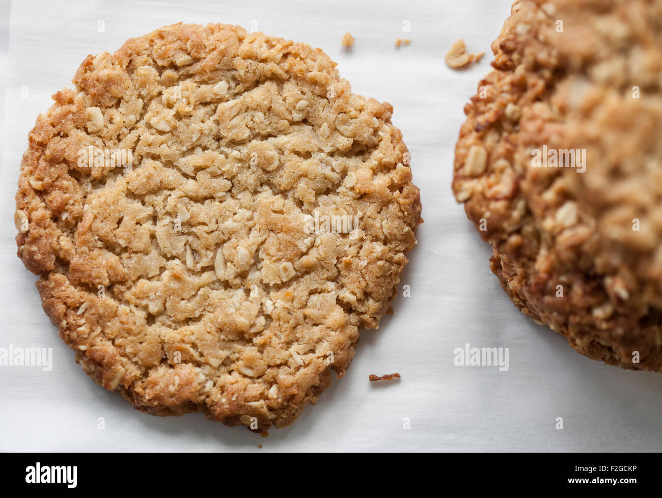 Mirando hacia abajo uno de los Anzac cookie con una pila a la derecha sobre blanco Foto de stock