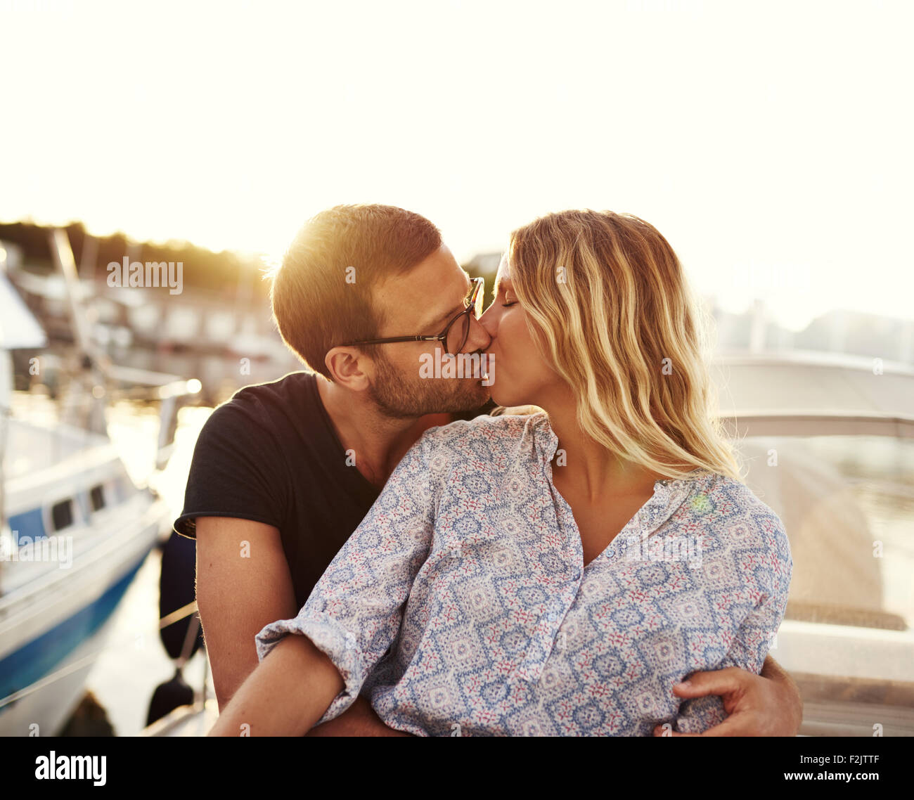 Un hombre y una mujer besándose en un barco, puesta de sol Foto de stock