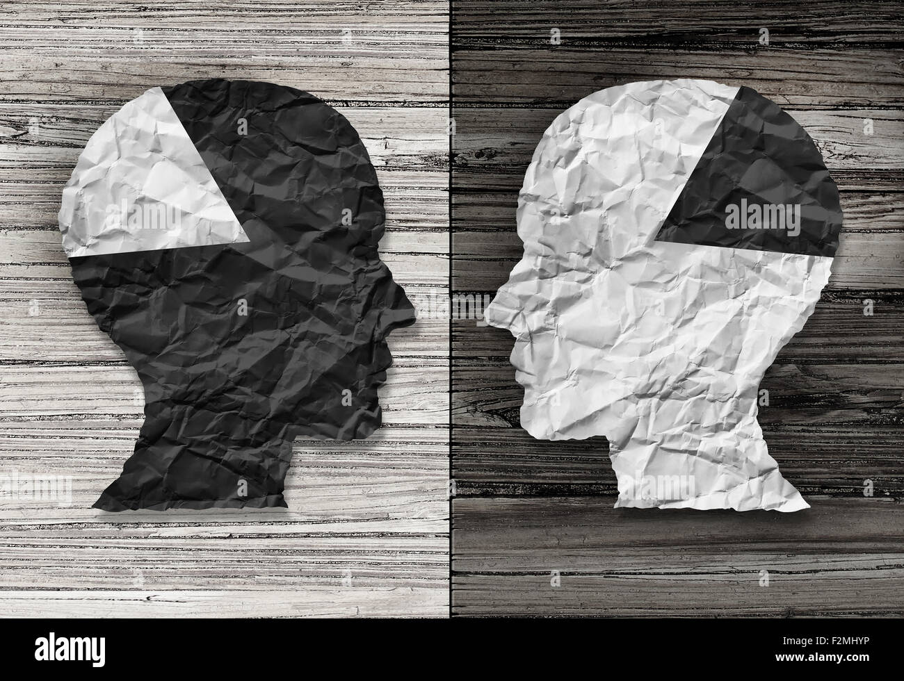 Concepto de igualdad étnica y la justicia racial símbolo como un papel arrugado en blanco y negro con la forma de una cabeza humana en madera rústica antigua Foto de stock