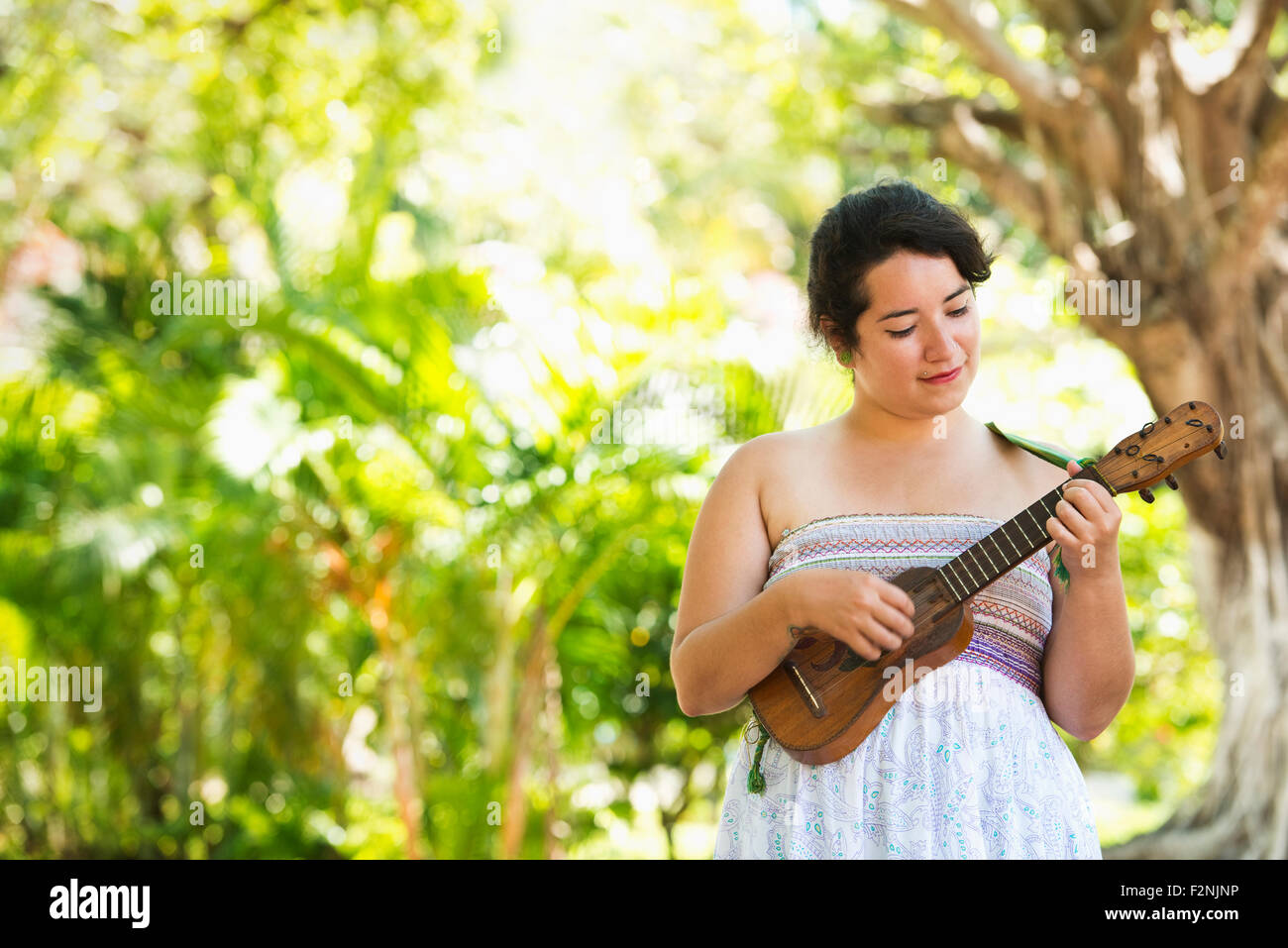 Hispanic músico tocando ukulele en estacionamiento Foto de stock