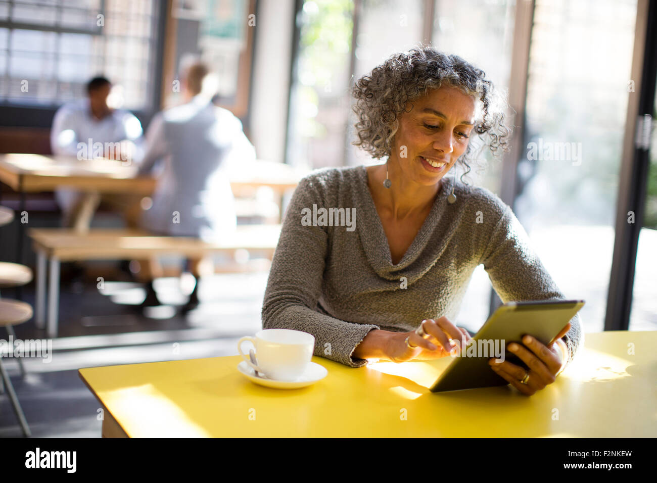 Mujer de edad utilizando digital comprimido en cafe Foto de stock