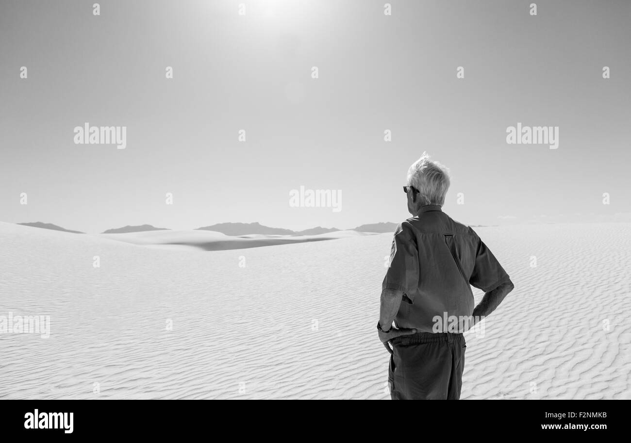 Hombre caucásico admirando las dunas de arena del desierto Foto de stock
