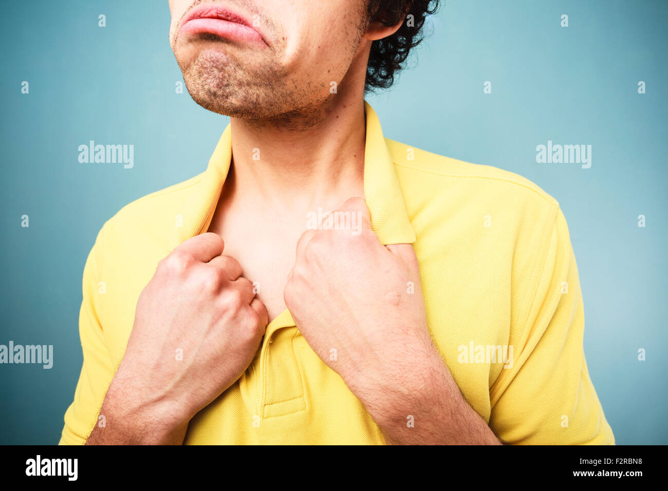 Hombre con una mirada triste en su rostro está tirando en el cuello de su camisa Foto de stock