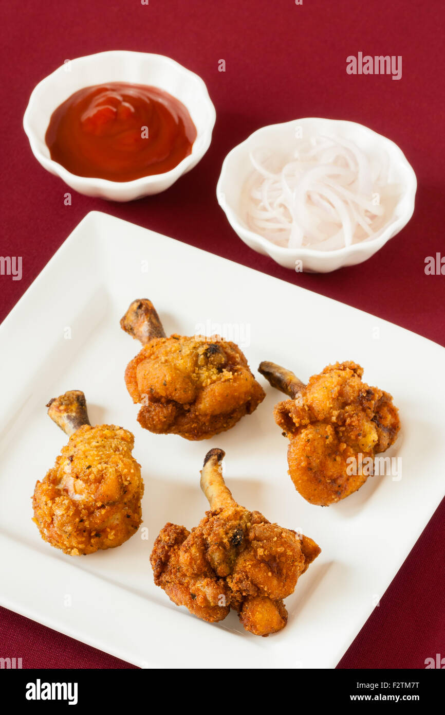 Acercamiento de Deep Fried Spicy Chicken lollipops servidos con tomate