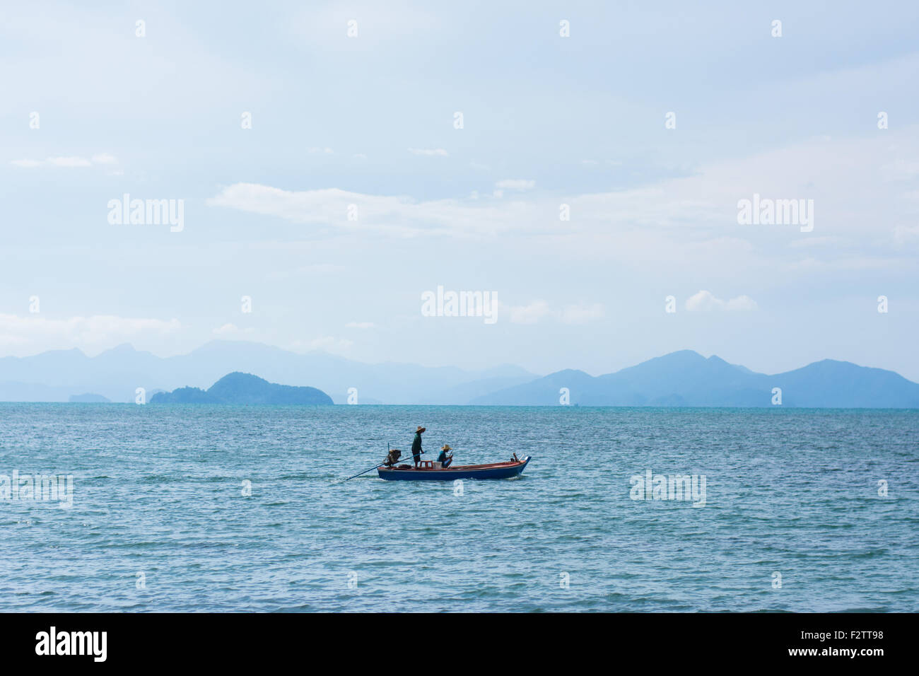Un pequeño barco pescador en el mar con las islas en el horizonte. Foto de stock