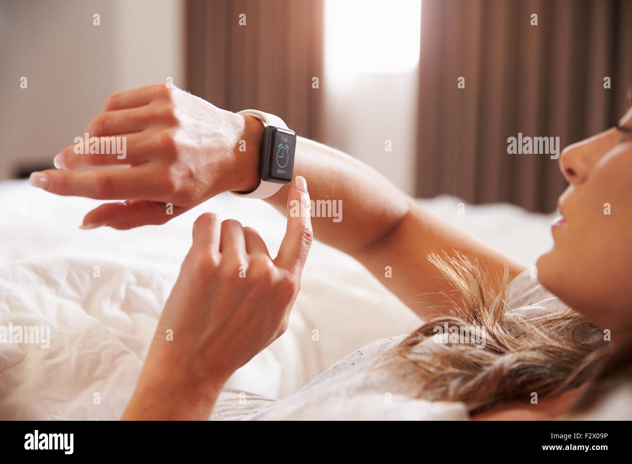 La mujer acostada en la cama Despertada por el despertador App en Smart  Watch Fotografía de stock - Alamy