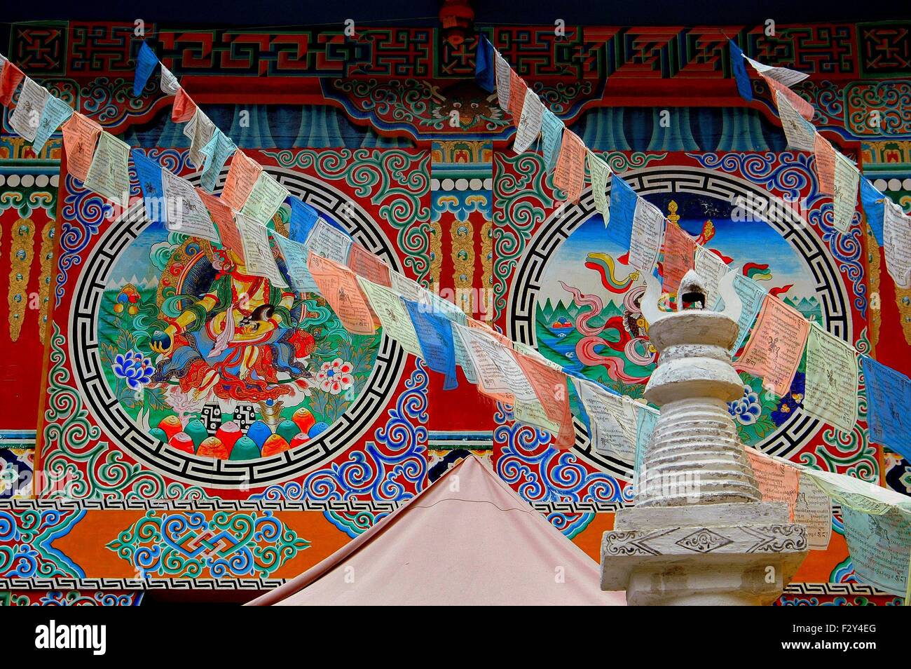 Jiu Zhai Gou / Sichuan, China: muro frescos adornan el lateral de un templo adornado con banderas de oración tibetano Foto de stock