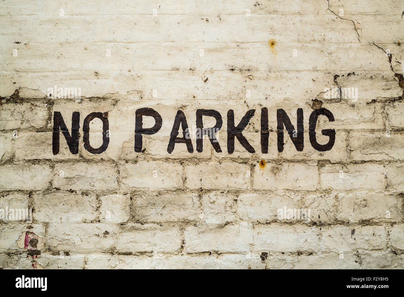 No hay señal de estacionamiento pintada a mano en negro sobre una pared de ladrillo blanco Foto de stock