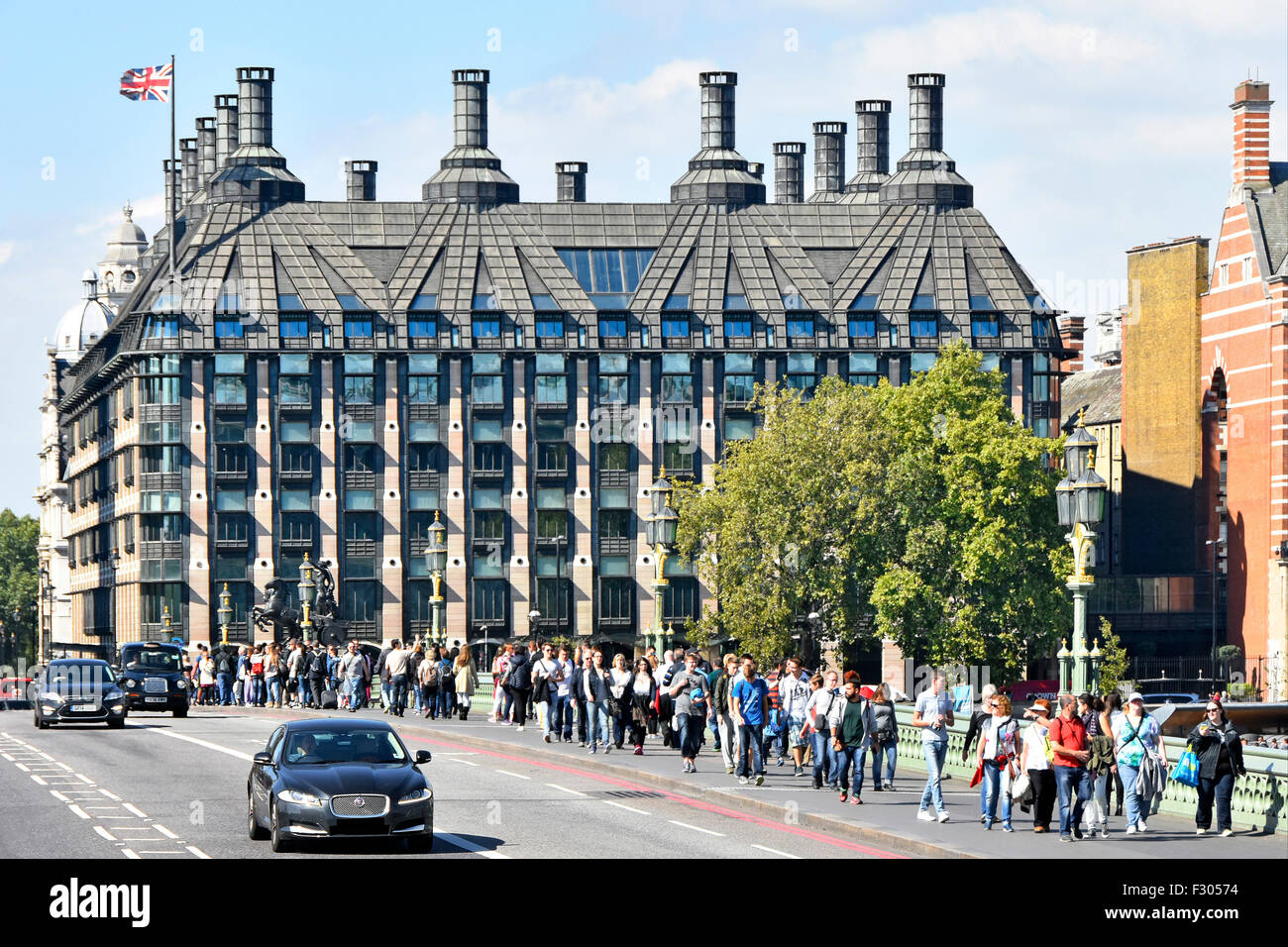 Portcullis House Londres complejo de oficinas para los miembros del Parlamento del Reino Unido con los turistas que caminan a lo largo de Westminster Bridge pavimento Inglaterra Foto de stock