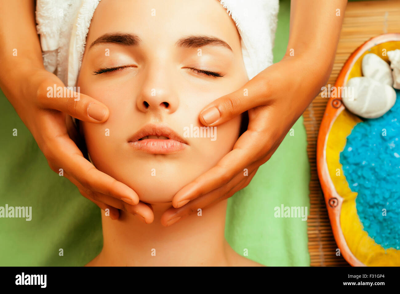 Stock Photo atractiva señora recibiendo tratamiento de spa en el salón, cerca de Asia hasta las manos en la cara Foto de stock