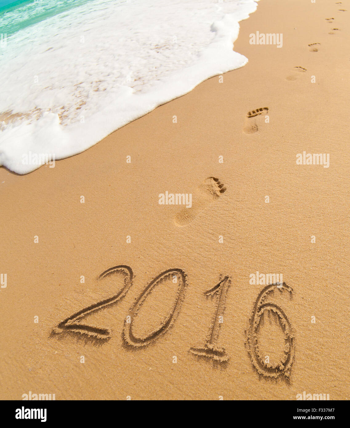 Año nuevo 2016 dígitos escrito en la arena de la playa Foto de stock