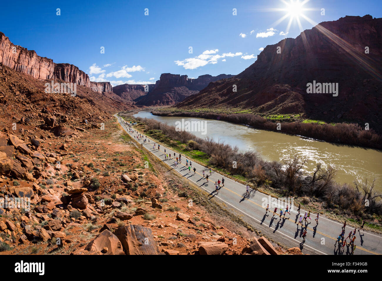 Grandes grupos de gente corriendo en una carretera próxima a un río durante una carrera. Foto de stock