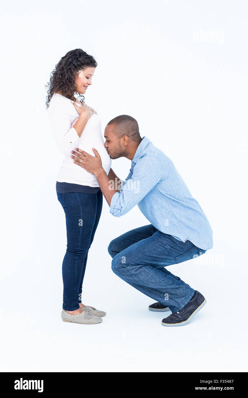 Hombre bese embarazada vientre contra el fondo blanco. Foto de stock