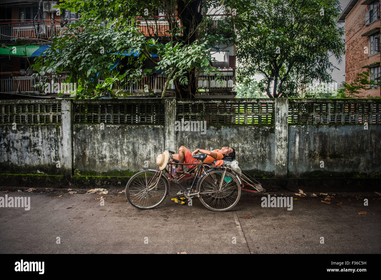 Ciclo taxista dormido en su bicicleta en Yangon, Myanmar. Foto de stock