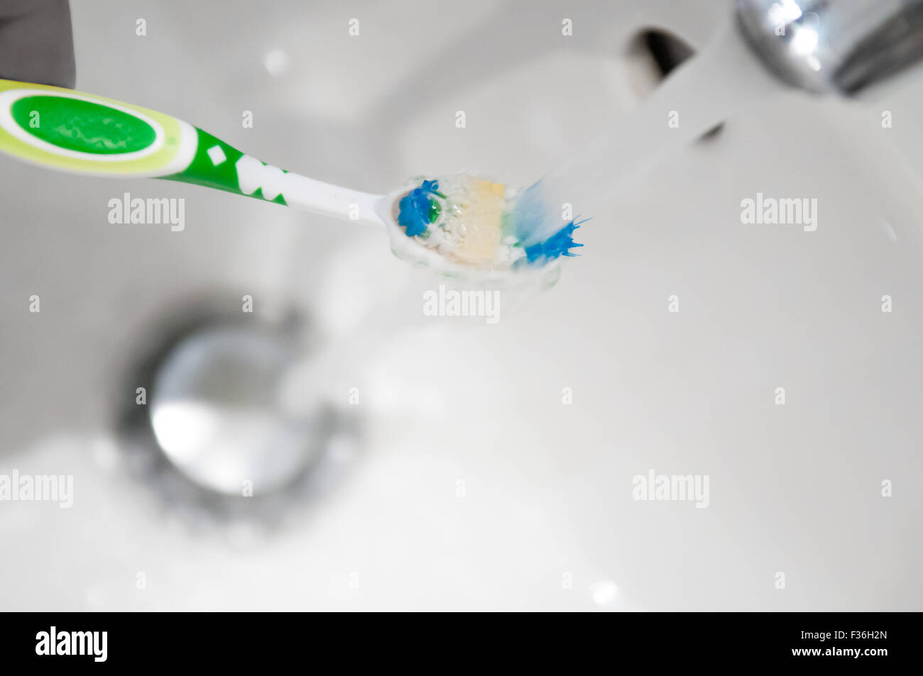 Cepillo de dientes se enjuaga bajo el grifo de agua de un grifo Foto de stock