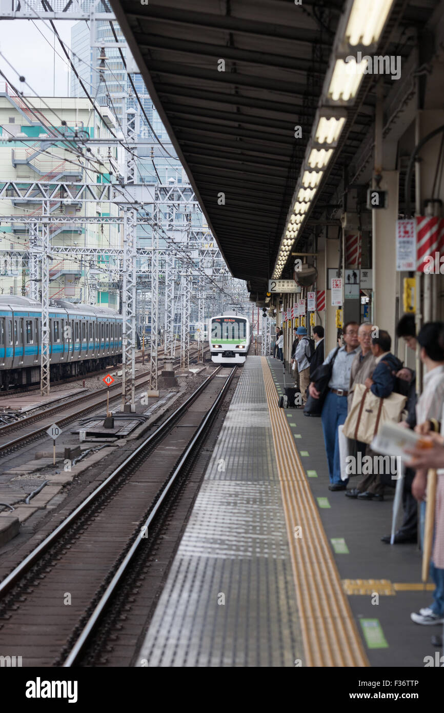 Plataforma con tren blanco verde en distancia Tokio JAPÓN Foto de stock