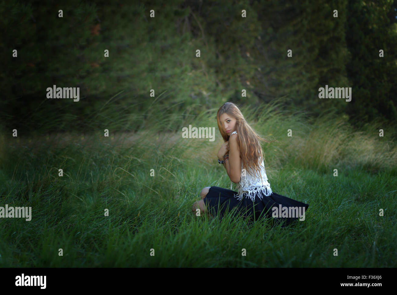 Misteriosa chica con el pelo largo en el bosque verde hierba Foto de stock
