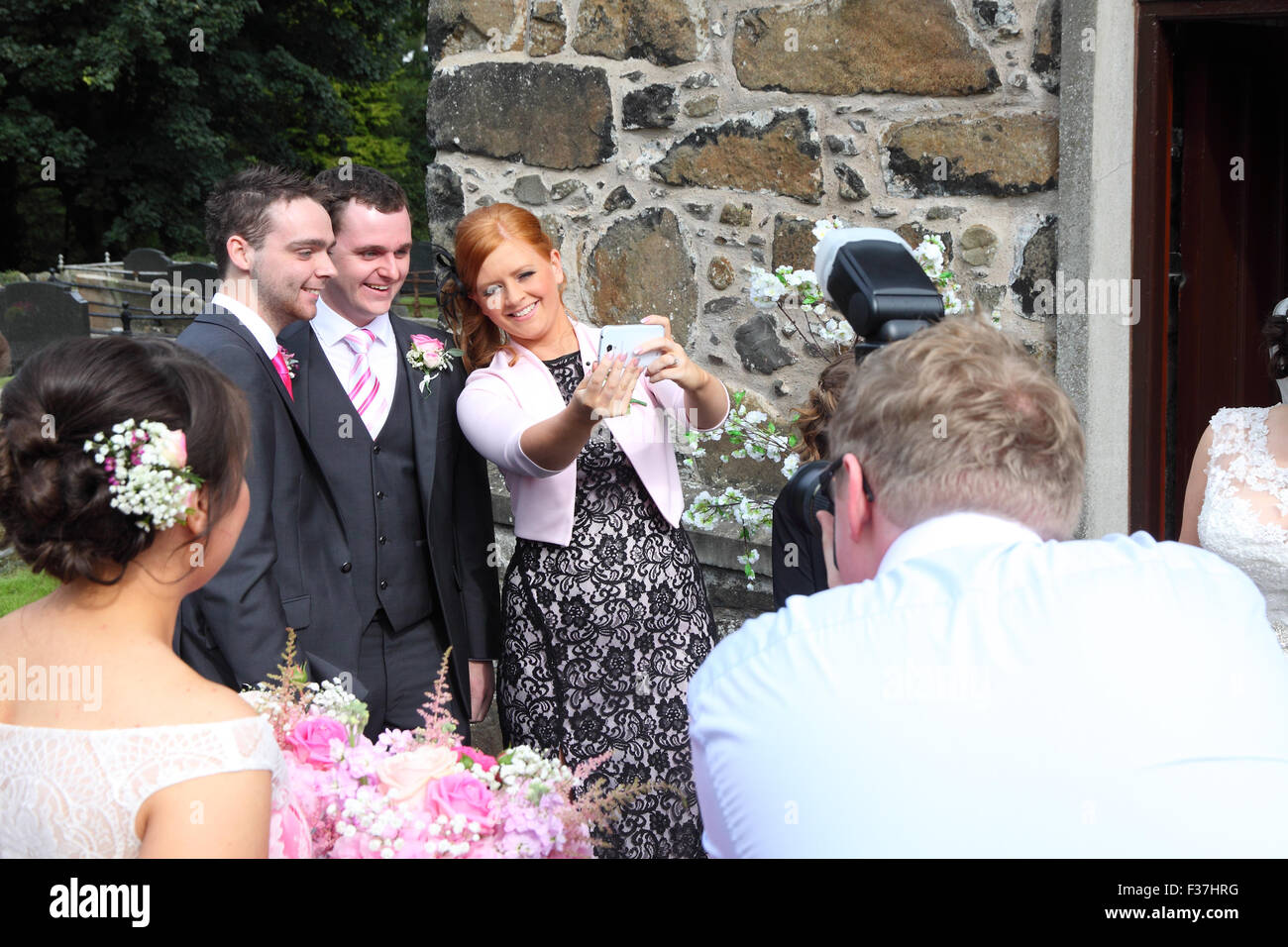 Fotógrafo de bodas tomar una fotografía de los invitados a la boda teniendo un selfie en un smartphone, REINO UNIDO Foto de stock