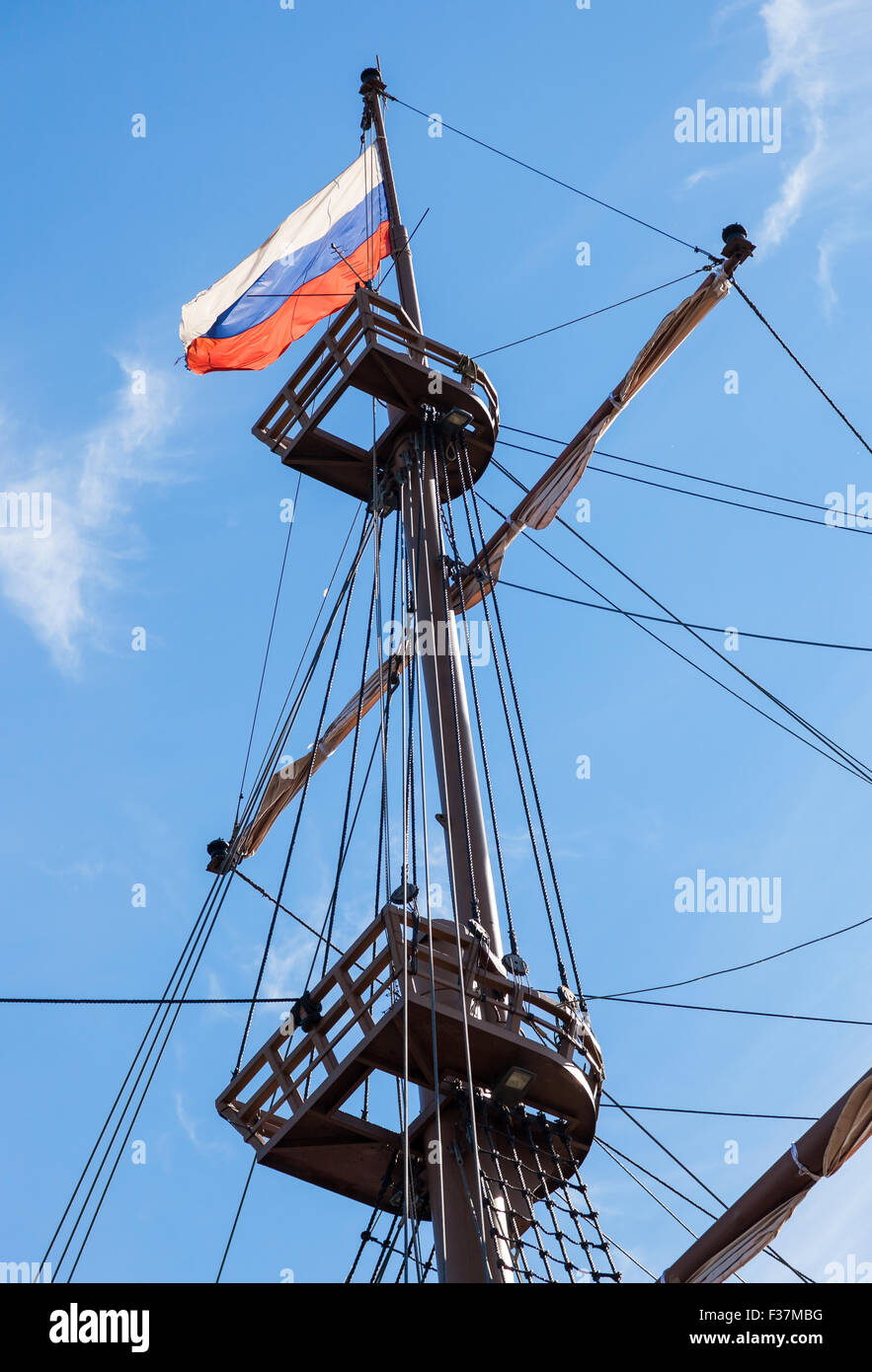 Ondea la bandera rusa sobre un mástil velero sobre un fondo de cielo azul Foto de stock
