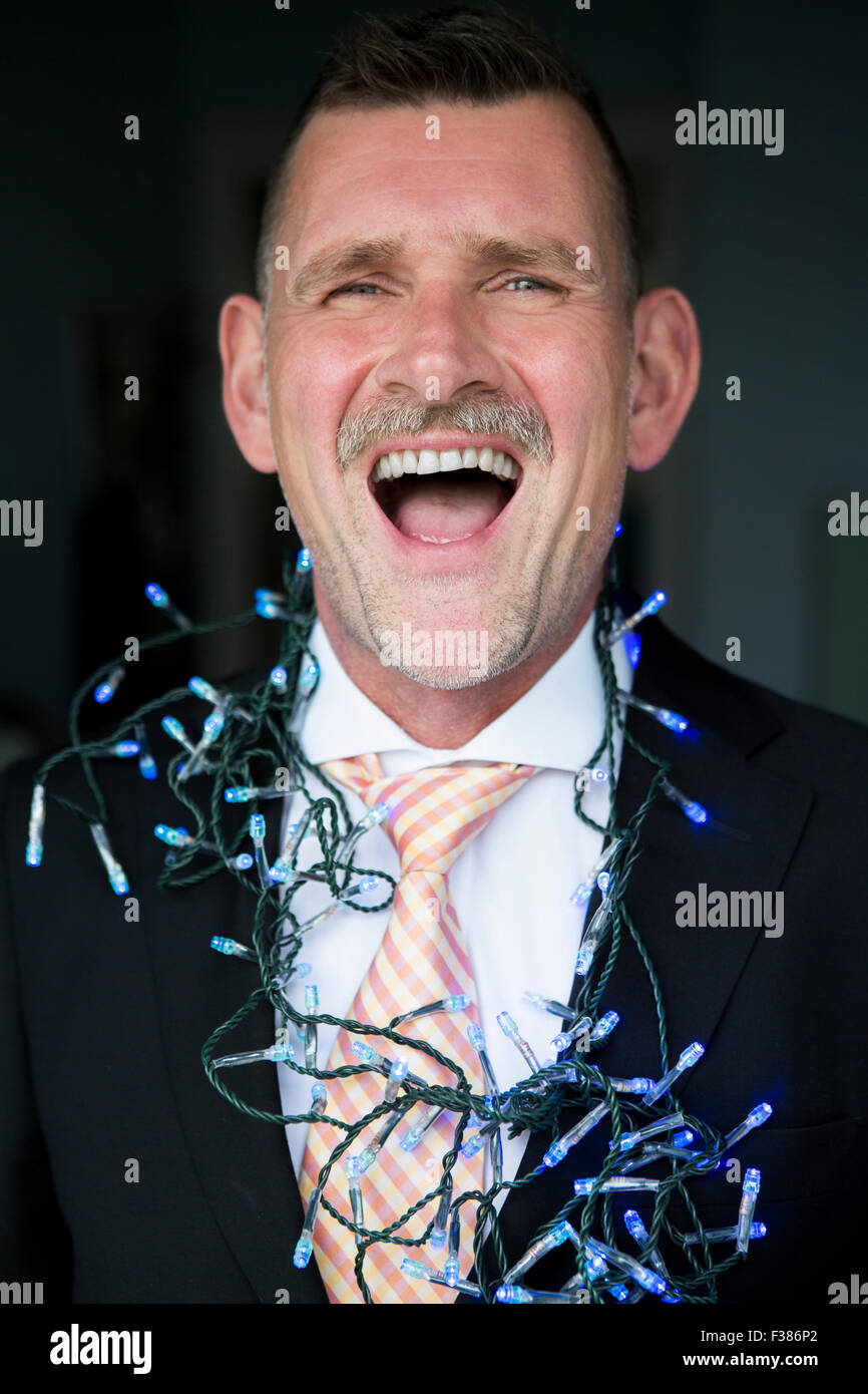 Retrato de empresario con luces de cadena y riendo Foto de stock