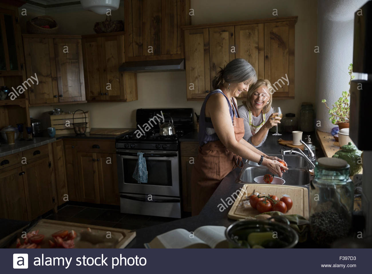 Las mujeres cocinar y beber vino en la cocina Foto de stock