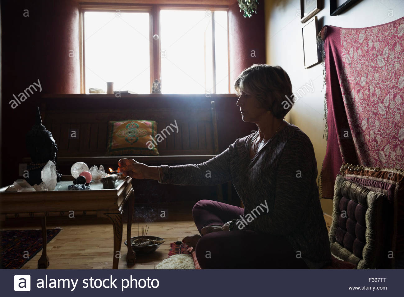 Senior Mujer encendiendo incienso en sala de meditación Foto de stock