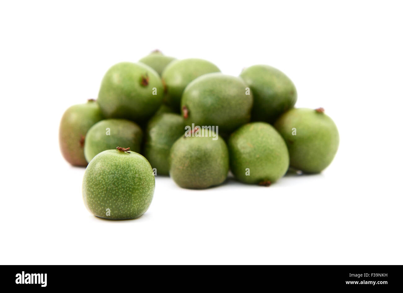 Kiwi berry en el enfoque selectivo contra el montón de bayas verdes, aislado en un fondo blanco. Foto de stock