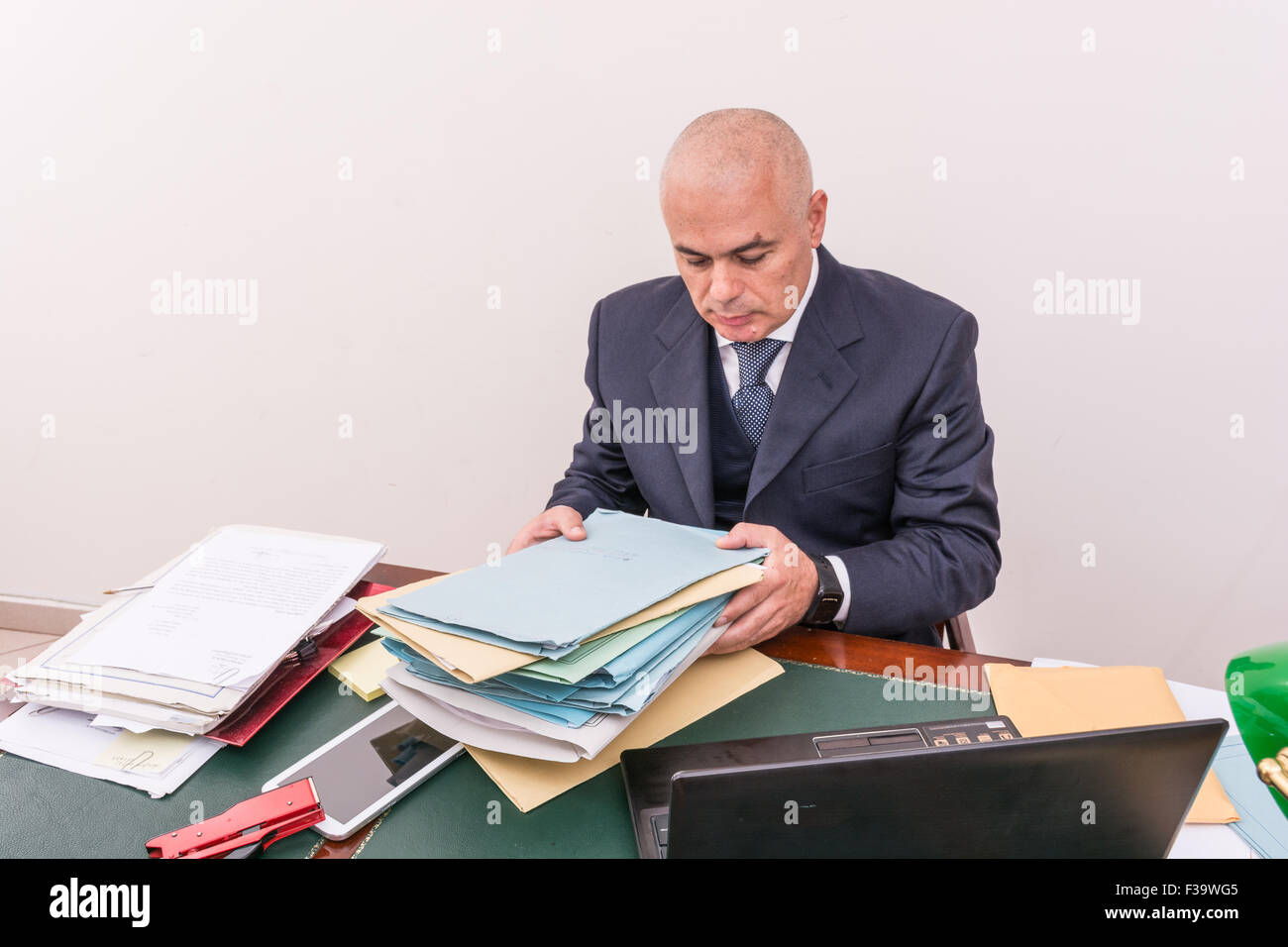 Hombre de negocios con sus archivos y documentos en el escritorio, en la oficina. En frente de la PC, el tablet en la mesa, y documentos en nad Foto de stock