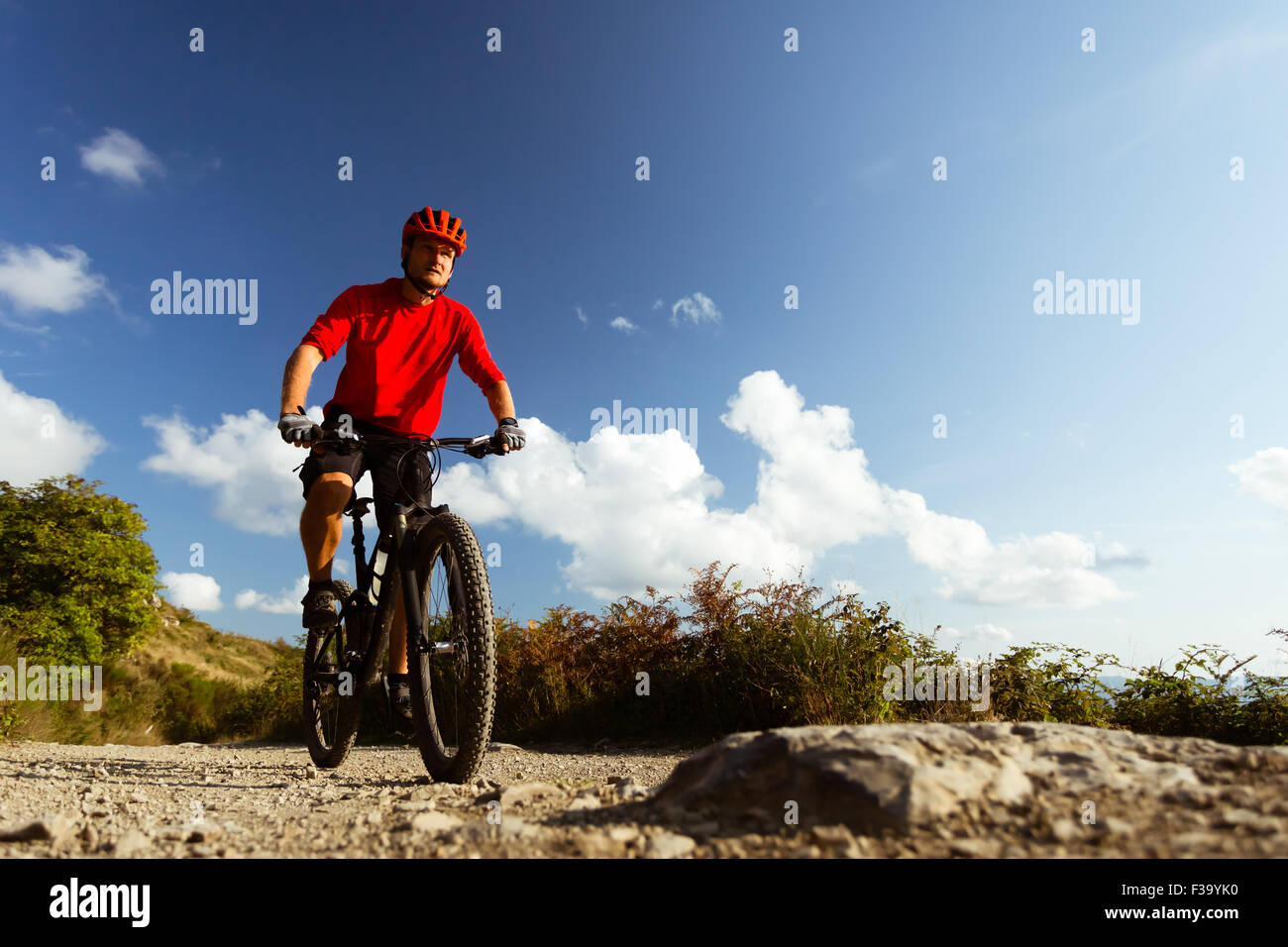 Hombre guapo ciclista en ropa deportiva y casco de pie con bicicleta en  carretera rural. Actividad al aire libre y estilos de vida saludables  Fotografía de stock - Alamy
