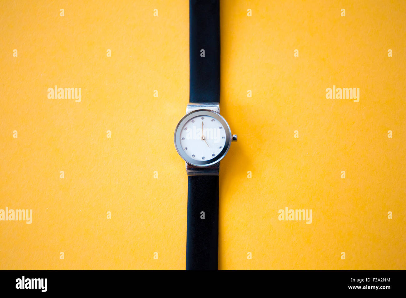 Reloj de pulsera moderno sobre fondo amarillo Foto de stock