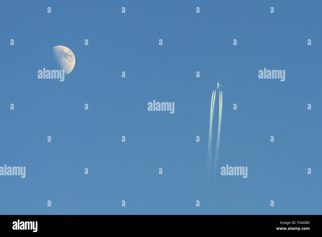 Un avión de pasajeros volando mientras half moon visibles en una luz del día Foto de stock
