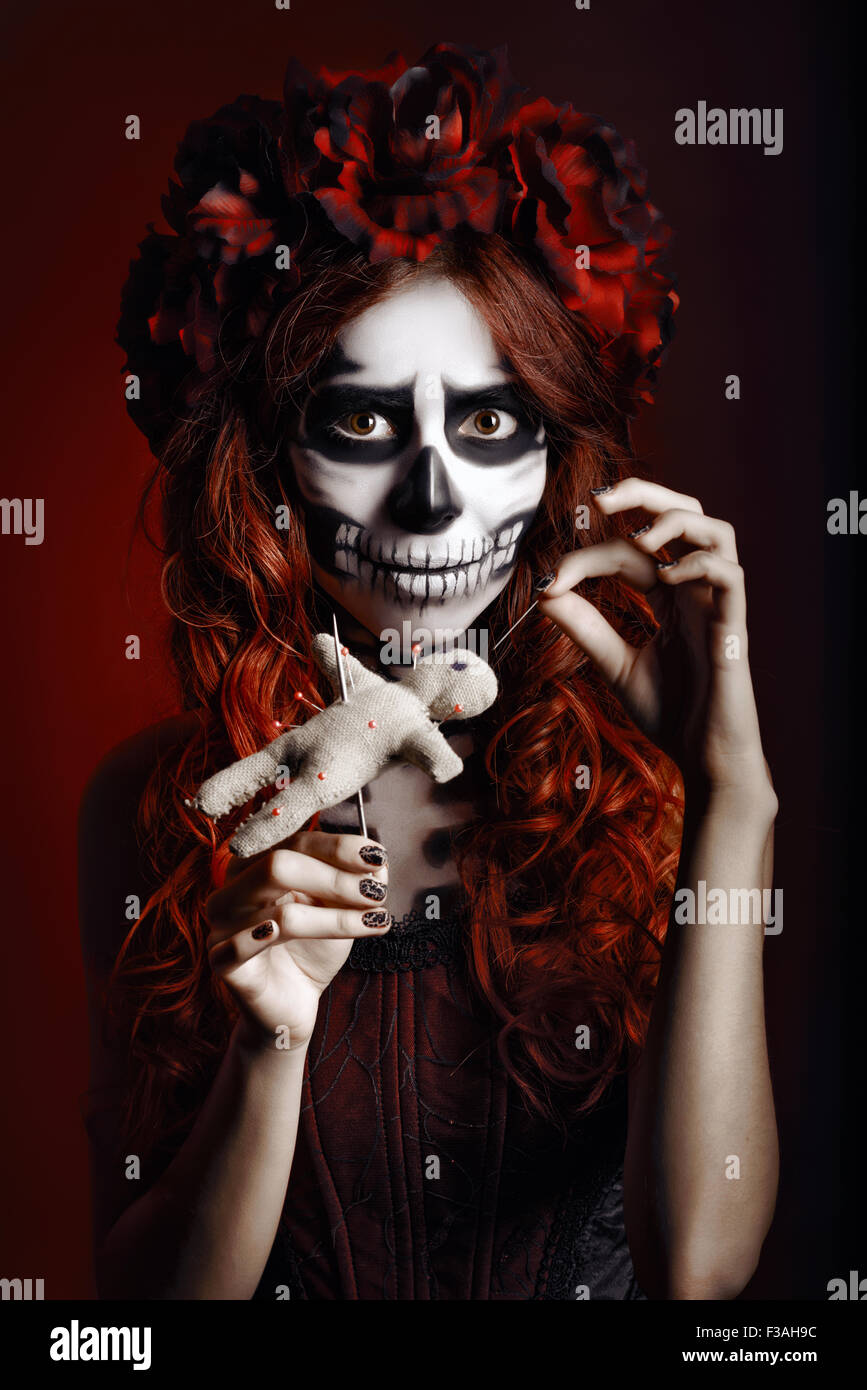 Mujer joven con maquillaje muertos (calaveras de azúcar) atravesando un  Voodoo doll Fotografía de stock - Alamy