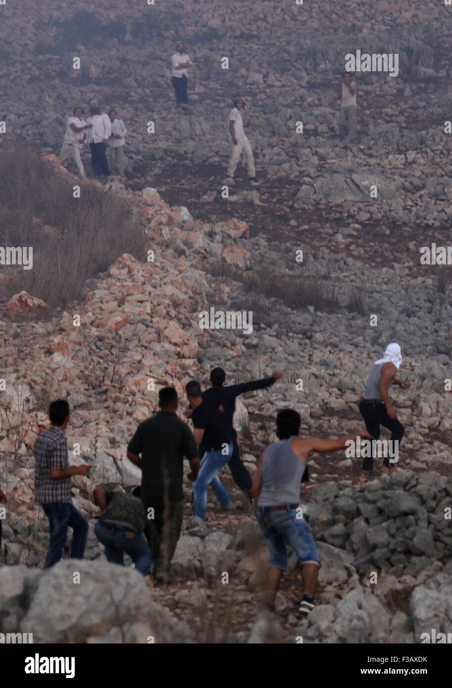 Nablus, Nablus. 3 Oct, 2015. Los palestinos arrojan piedras contra los colonos israelíes durante los enfrentamientos ocurridos en la aldea de la Ribera Occidental de Burin, cerca de Naplusa, el 3 de octubre de 2015. Esporádicos enfrentamientos entre palestinos y una docena de colonos del asentamiento de Yitzhar cuando los colonos arrojaron piedras a los palestinos que han respondido de la misma manera. © Nidal Eshtayeh/Xinhua/Alamy Live News Foto de stock